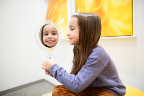 Child Smiling and Holding Mirror